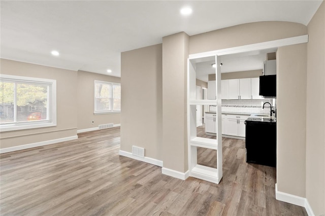 kitchen featuring decorative backsplash, white cabinetry, sink, and light hardwood / wood-style floors