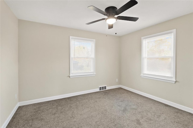 spare room with a wealth of natural light, ceiling fan, and carpet floors