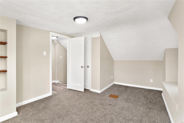 bonus room with lofted ceiling, a textured ceiling, and dark colored carpet