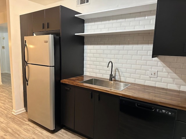 kitchen featuring wood counters, dishwasher, sink, and stainless steel fridge