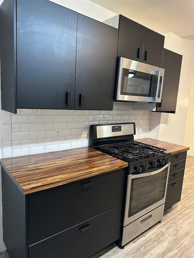 kitchen featuring backsplash, butcher block counters, stainless steel appliances, and light wood-type flooring