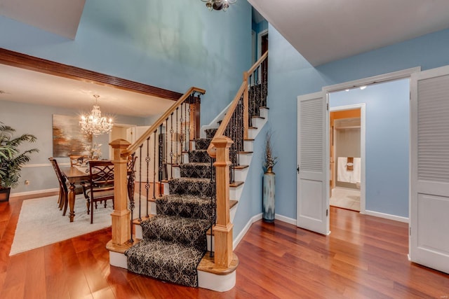 staircase with wood-type flooring and a notable chandelier