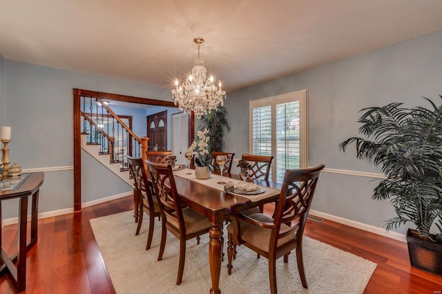 dining room with dark hardwood / wood-style flooring and an inviting chandelier