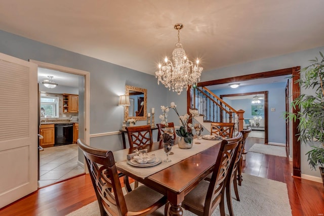 dining room with ceiling fan with notable chandelier and light wood-type flooring