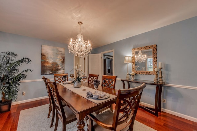 dining room with dark wood-type flooring and an inviting chandelier