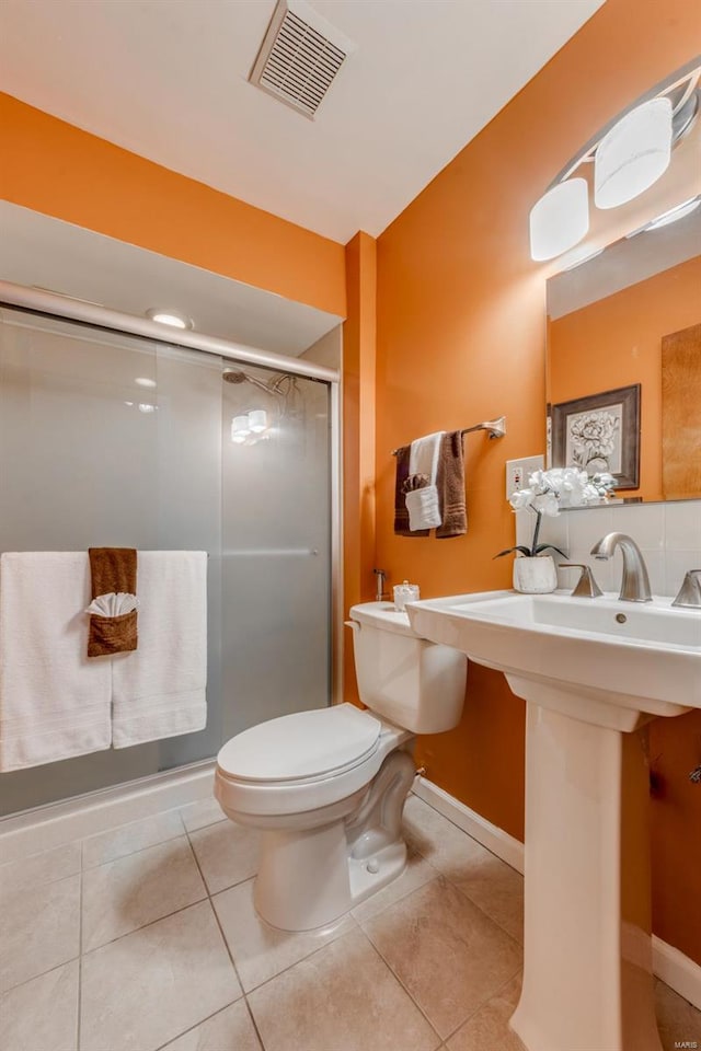 bathroom with tile patterned flooring, toilet, and an enclosed shower