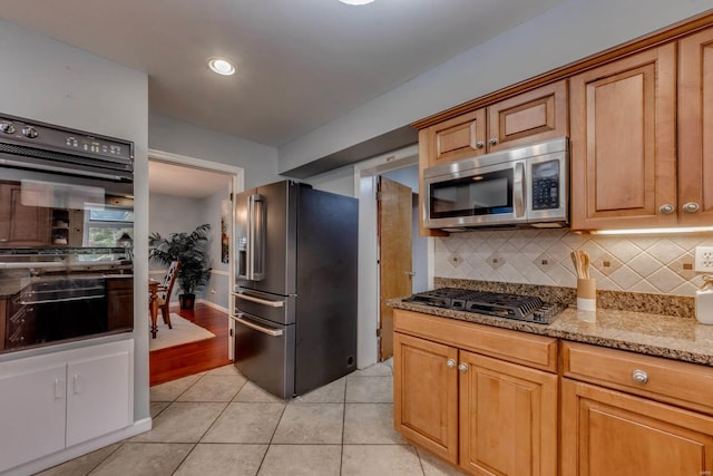 kitchen featuring decorative backsplash, stainless steel appliances, light tile patterned floors, and light stone counters