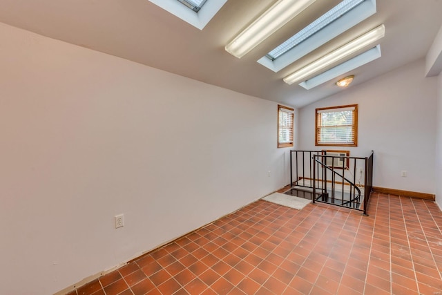 tiled spare room with lofted ceiling with skylight