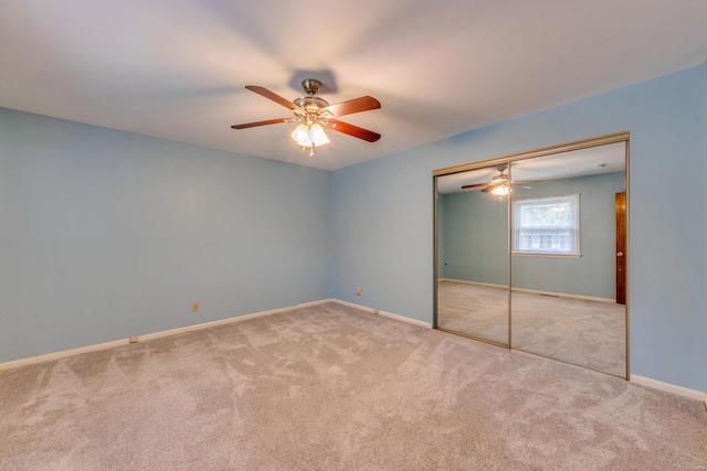 unfurnished bedroom with a closet, light colored carpet, and ceiling fan