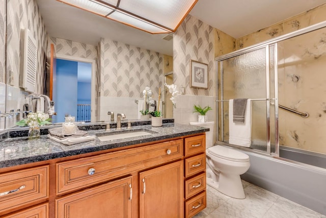 full bathroom featuring toilet, bath / shower combo with glass door, and vanity