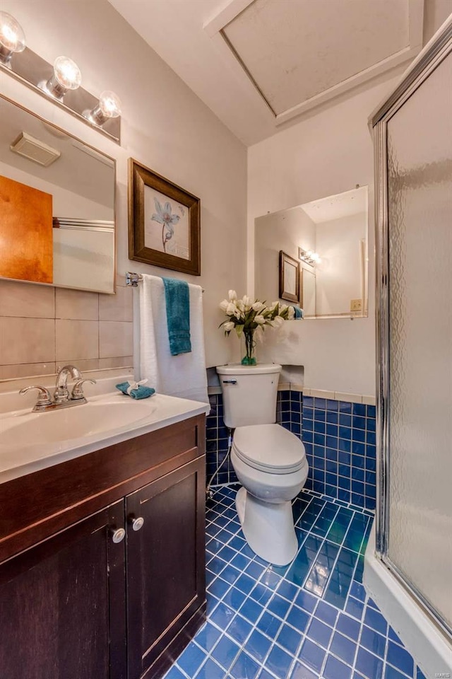 bathroom with tile patterned floors, toilet, tile walls, vanity, and walk in shower