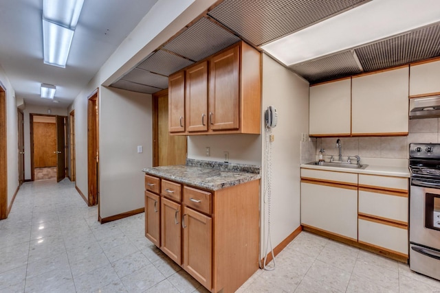 kitchen featuring stainless steel range, decorative backsplash, exhaust hood, and sink