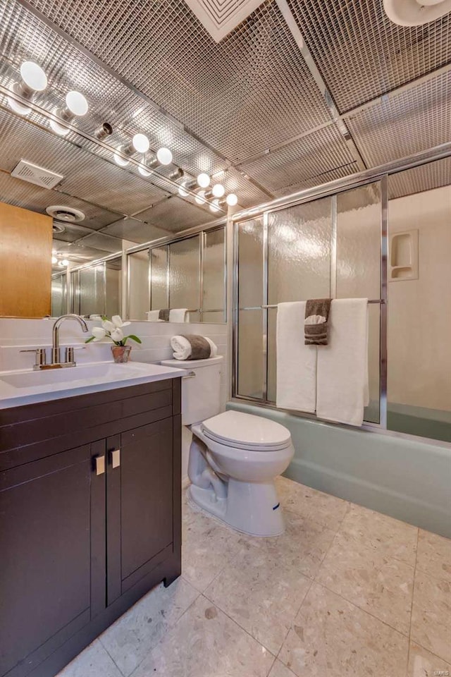 full bathroom with combined bath / shower with glass door, tile patterned flooring, vanity, and toilet