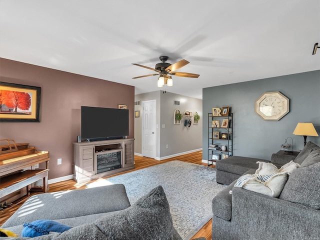 living room featuring wood finished floors, baseboards, and ceiling fan