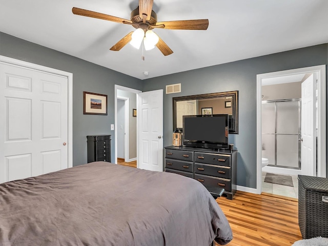 bedroom featuring light wood-style flooring, a ceiling fan, visible vents, baseboards, and ensuite bathroom