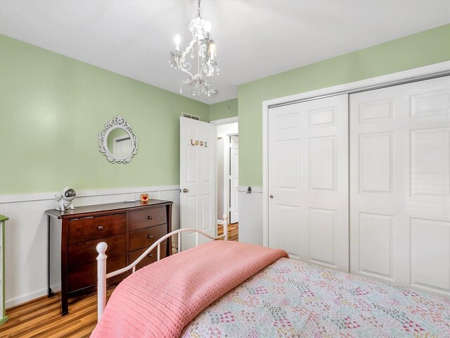 bedroom with wainscoting, a chandelier, a closet, and wood finished floors