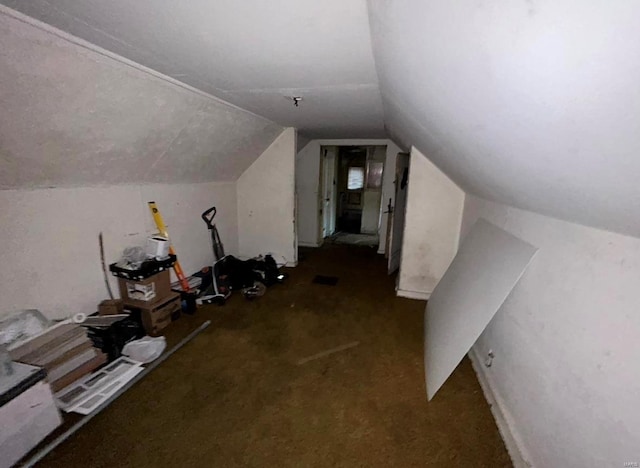 additional living space with dark colored carpet and vaulted ceiling