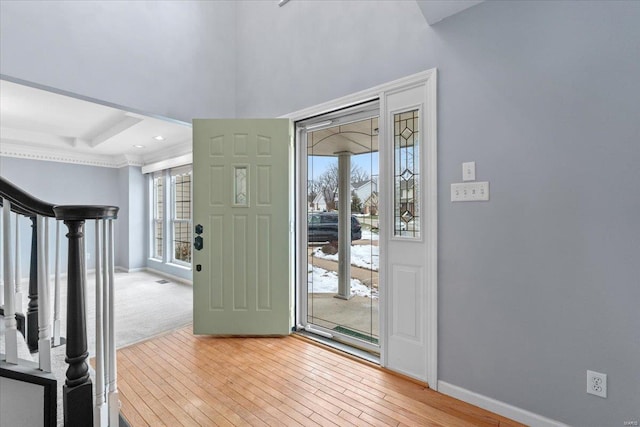 foyer with a raised ceiling and light wood-type flooring