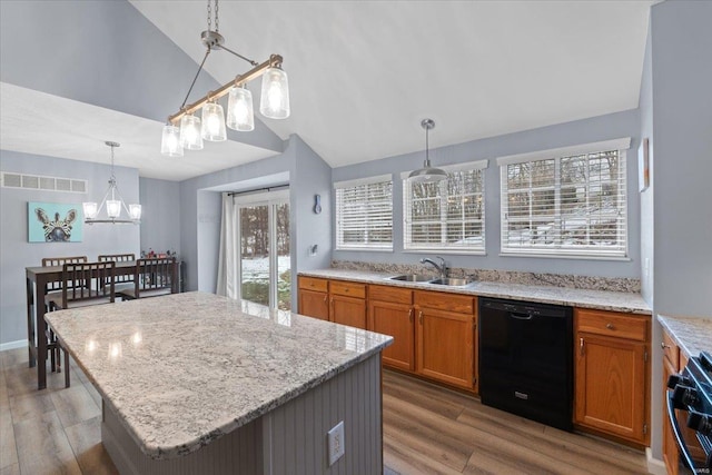 kitchen with a kitchen island, sink, hanging light fixtures, light stone counters, and black appliances