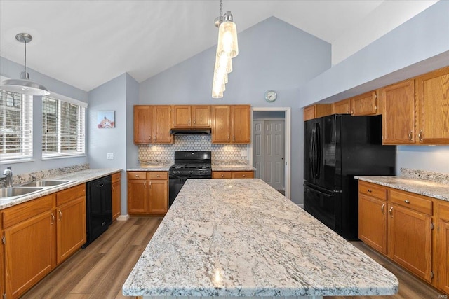 kitchen with lofted ceiling, sink, a center island, black appliances, and decorative light fixtures