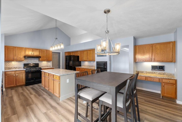 kitchen featuring a center island, hardwood / wood-style floors, hanging light fixtures, and black appliances