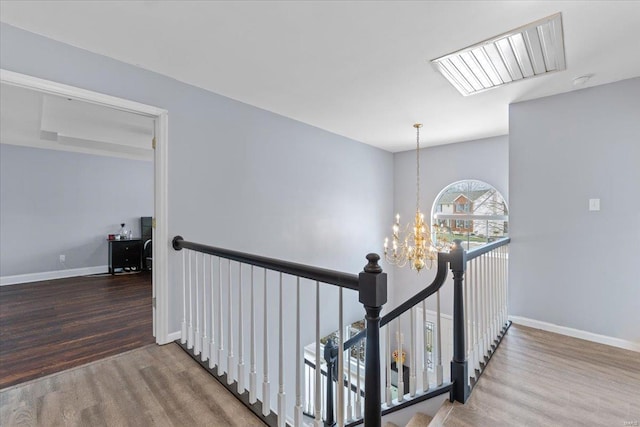 hallway with a skylight, hardwood / wood-style floors, and a notable chandelier