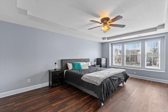 bedroom featuring dark hardwood / wood-style flooring, a raised ceiling, and ceiling fan