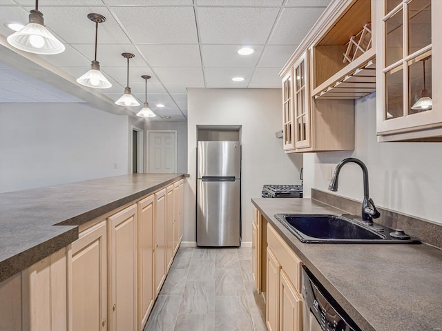 kitchen featuring appliances with stainless steel finishes, a paneled ceiling, sink, light brown cabinets, and decorative light fixtures