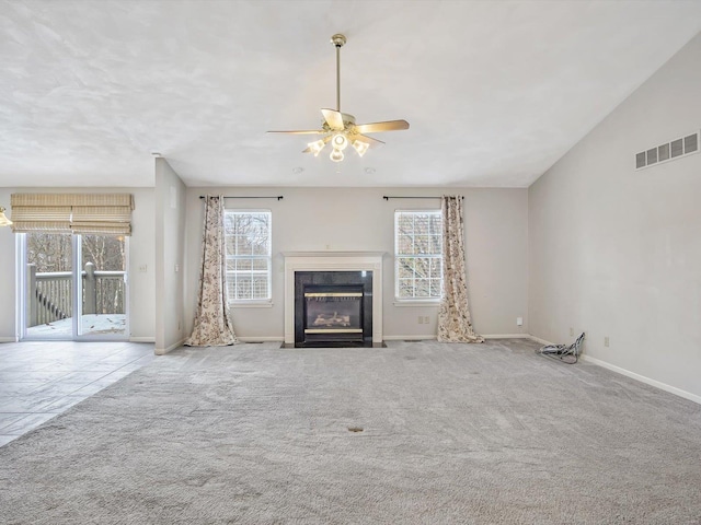 unfurnished living room with plenty of natural light, ceiling fan, light carpet, and vaulted ceiling