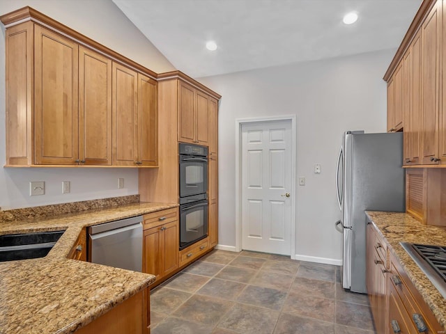 kitchen featuring light stone countertops, sink, vaulted ceiling, and appliances with stainless steel finishes