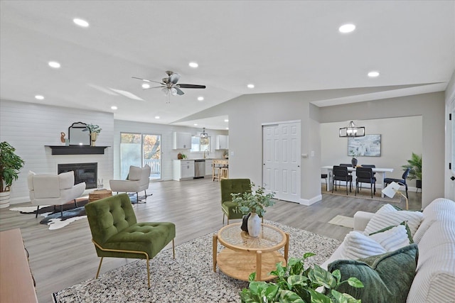 living room with lofted ceiling, sink, light hardwood / wood-style flooring, ceiling fan, and a large fireplace