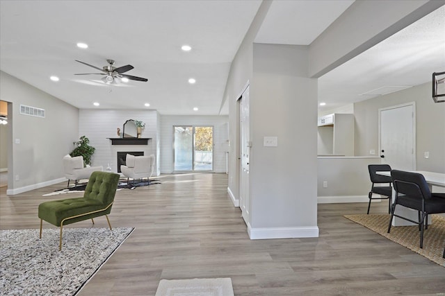 foyer featuring ceiling fan, light wood-type flooring, and a fireplace