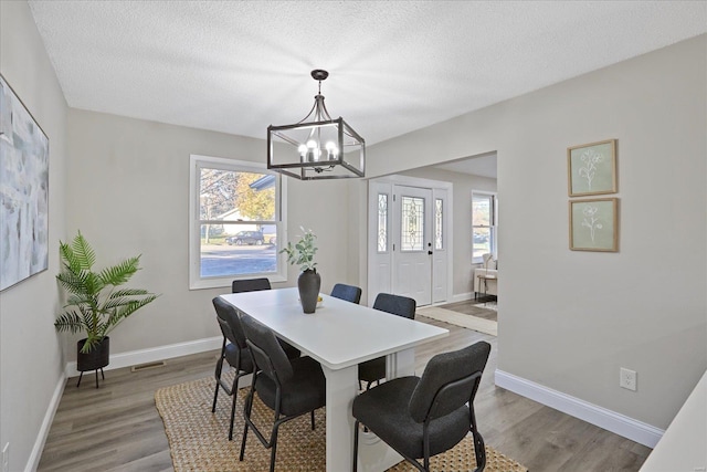 dining area featuring hardwood / wood-style flooring, a textured ceiling, and a chandelier