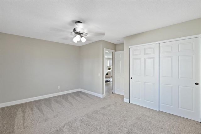 unfurnished bedroom featuring ceiling fan, light colored carpet, a textured ceiling, and a closet