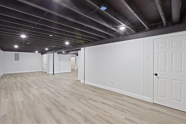 basement with light wood-type flooring and electric panel