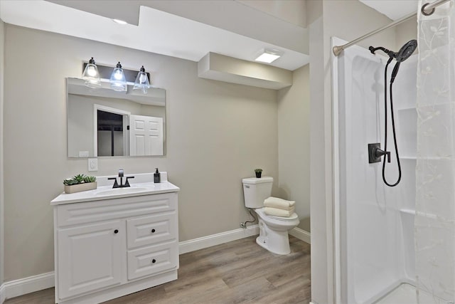 bathroom with hardwood / wood-style floors, vanity, toilet, and walk in shower