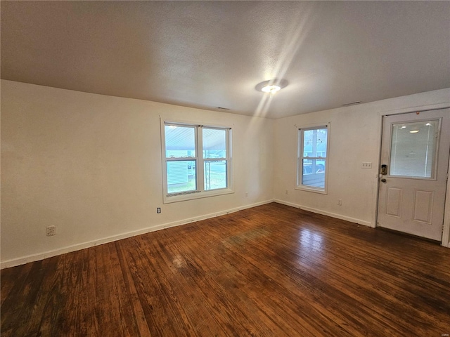 interior space with a textured ceiling and dark hardwood / wood-style floors