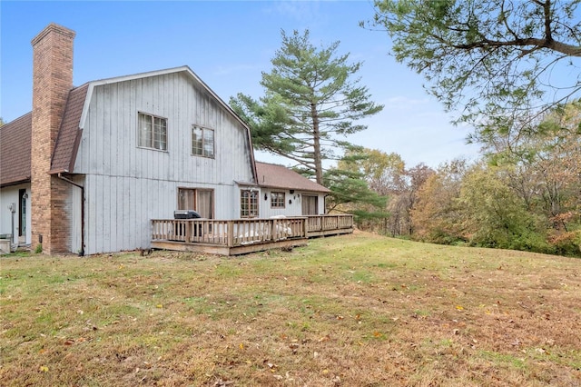 rear view of property featuring a wooden deck and a lawn