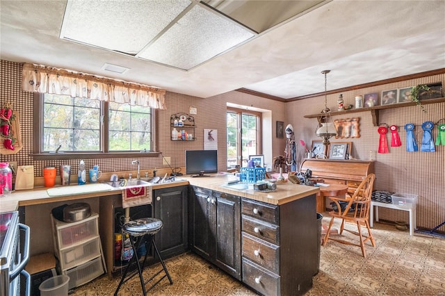 kitchen featuring stainless steel range, kitchen peninsula, a healthy amount of sunlight, and hanging light fixtures