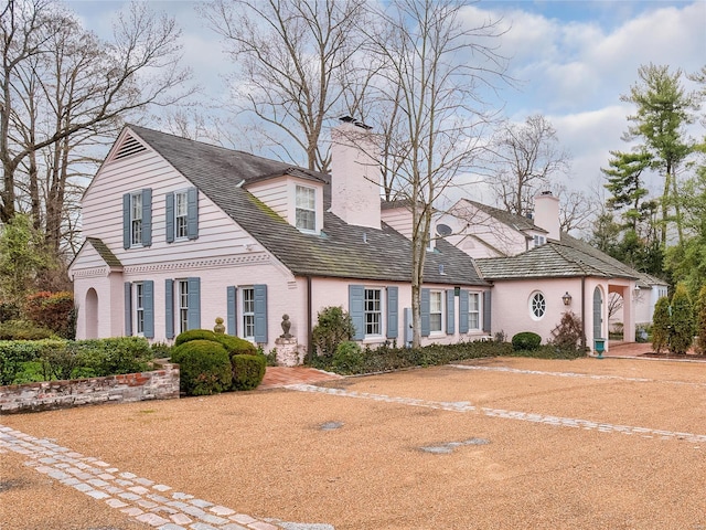 view of front of house with brick siding and a chimney