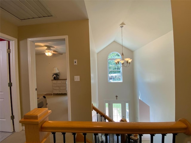 hall featuring a chandelier, vaulted ceiling, and carpet