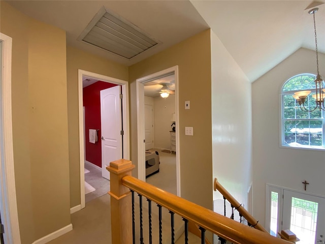 hallway featuring lofted ceiling, carpet flooring, a wealth of natural light, and an inviting chandelier