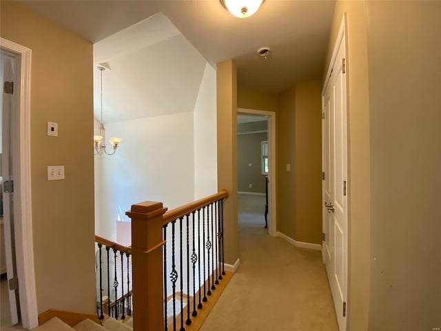 corridor featuring light carpet and a notable chandelier