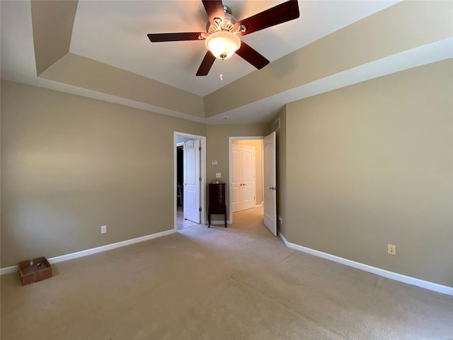 interior space featuring light colored carpet, a tray ceiling, and ceiling fan