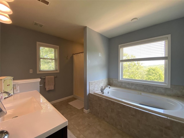 bathroom with vanity, independent shower and bath, a wealth of natural light, and tile patterned flooring