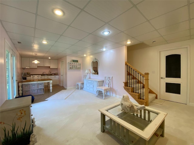 living room with light carpet and a paneled ceiling