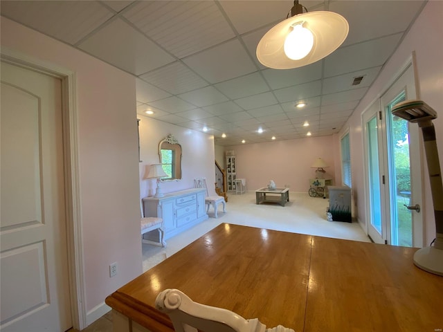 unfurnished dining area with a paneled ceiling and light colored carpet