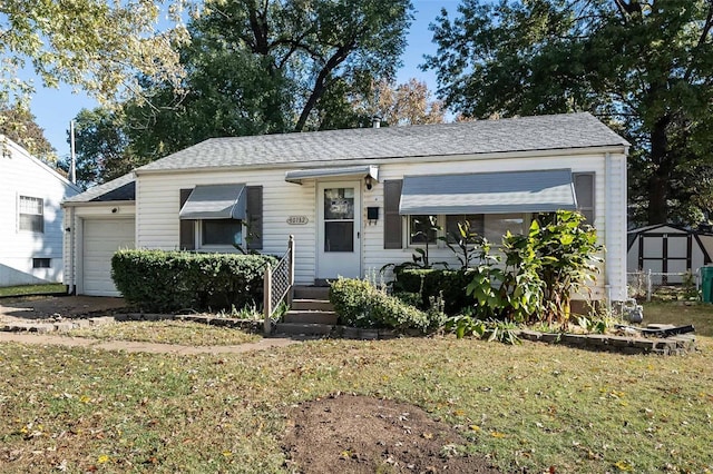 view of front of home with a front yard, a shed, and a garage