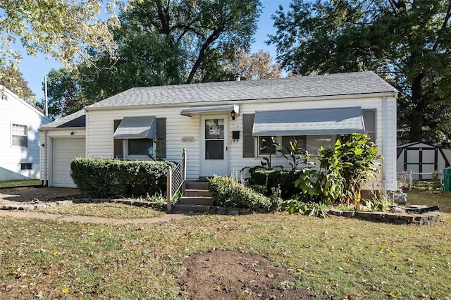 bungalow-style house with roof with shingles, an attached garage, a shed, and a front yard