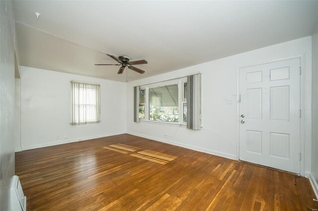 interior space featuring baseboards, ceiling fan, a baseboard heating unit, and wood finished floors